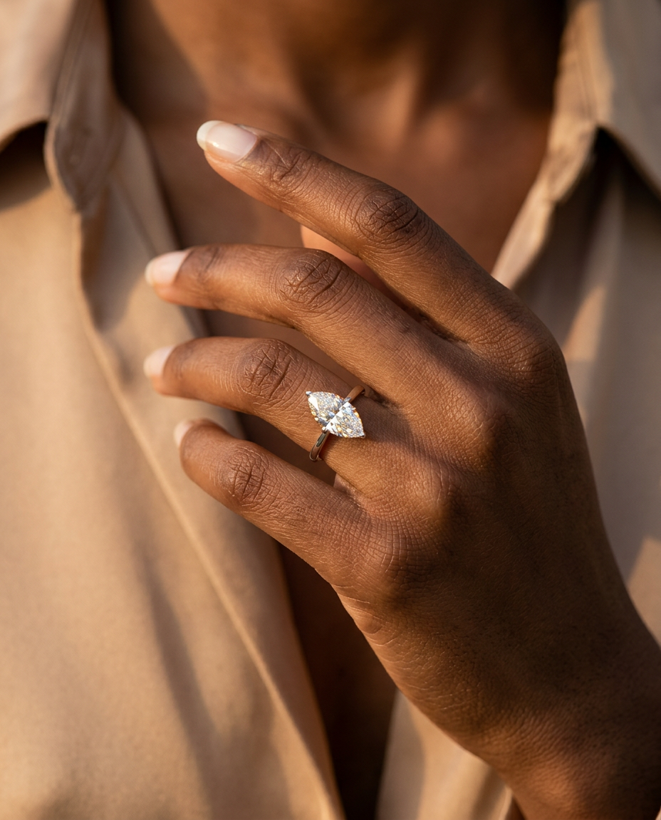 Mira marquise ring on a model's hand near the collarbone in golden light